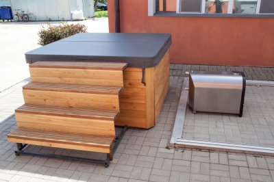 Гидромассажная ванна с деревянной отделкой на плиточной площадке с лестницей